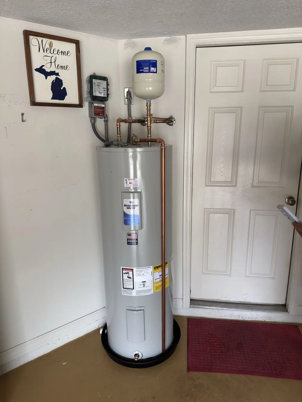 Installed residential water heater with expansion tank beside a doorway